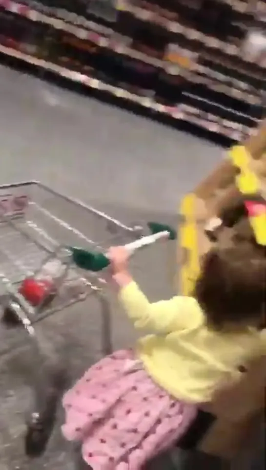 Little girl throws a bottle of wine in her toy trolley