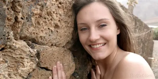 Busty brunette gets naked between two rock walls.