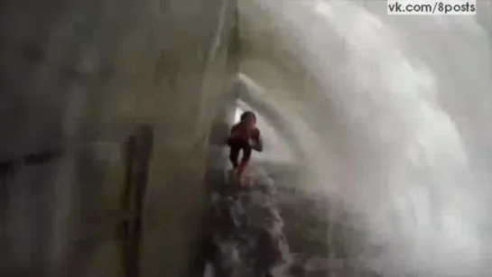 Сёрферы спрятались за камнем от волн, падающих на набережную / Huge waves pass over the surfers