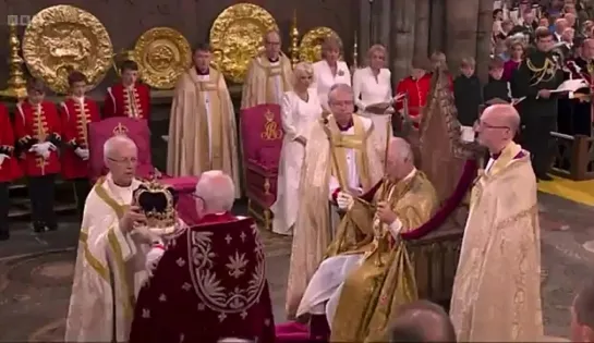 The Archbishop of Canterbury crowns King Charles III. - - Cries of God Save The King fill