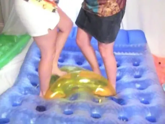 Two girls inflates, sitting and popping pool toys